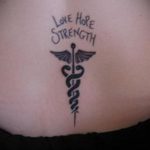 Фото тату на спине: надпись "Love, Hope, Strength" над символом Эскулапа (змея с крыльями). Символичный и вдохновляющий дизайн.