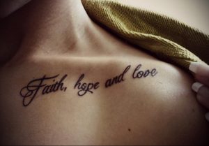 Фото тату на ключице: надпись "Faith, hope and love" изящным каллиграфическим шрифтом черными чернилами. Нежный и вдохновляющий дизайн.