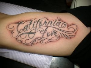 Фото тату на руке: надпись "California Love" изящным каллиграфическим шрифтом в черно-серых тонах. Стильный и оригинальный дизайн.