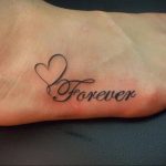 Фото татуировки на стопе с надписью 'Forever' и изображением сердца. Черно-серый рисунок, выполненный в минималистичном стиле.