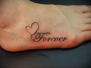 Фото татуировки на стопе с надписью 'Forever' и изображением сердца. Черно-серый рисунок, выполненный в минималистичном стиле.