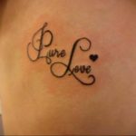 Фото тату надписи "Pure Love" выполненной каллиграфическим шрифтом с маленьким сердечком на боку девушки. Черно-белая татуировка, нежный дизайн.