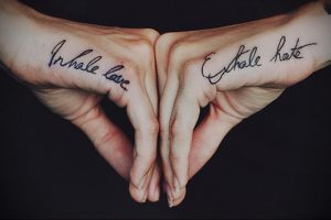 Фото тату надписи 'Inhale Love, Exhale Hate' на ладонях. Каллиграфический шрифт и глубокий смысл делают эту татуировку особенной.