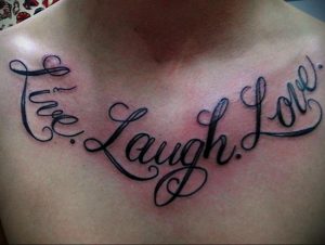 Фото тату надписи 'Live Laugh Love' на груди. Изящный шрифт и плавные линии создают красивый и гармоничный рисунок.