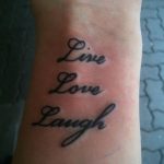 Фото тату: надпись 'Live, Love, Laugh' каллиграфическим шрифтом на запястье. Популярный и позитивный рисунок татуировки.