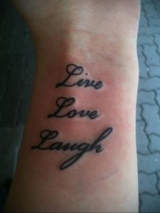 Фото тату: надпись 'Live, Love, Laugh' каллиграфическим шрифтом на запястье. Популярный и позитивный рисунок татуировки.