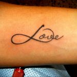 Фото тату: символ бесконечности с надписью 'Love' внутри, выполненная черными чернилами на запястье. Простой и элегантный рисунок татуировки.