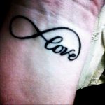 Фото тату на руке. Слово «Love» вписанное в символ бесконечности, черная татуировка, минималистичный стиль, идеи для девушек.