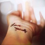 Фото тату с надписью «Love Yourself» на запястье. Черная татуировка, минималистичный стиль, вдохновение для девушек, мотивационная татуировка.