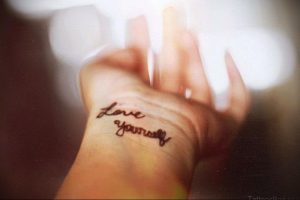 Фото тату с надписью «Love Yourself» на запястье. Черная татуировка, минималистичный стиль, вдохновение для девушек, мотивационная татуировка.