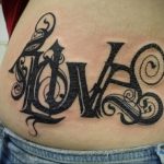 Фото татуировки надписью 'LOVE' на боку. Большой рисунок татуировки с декоративными элементами и черными узорами.