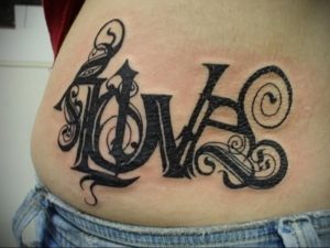 Фото татуировки надписью 'LOVE' на боку. Большой рисунок татуировки с декоративными элементами и черными узорами.
