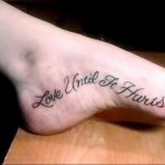 Фотография черной татуировки с надписью 'Love Until It Hurts' на стопе. Изящный шрифт и романтичный посыл.