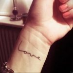 Фотография черной татуировки с надписью 'Love' на запястье. Минималистичный дизайн и изящный шрифт делают татуировку стильной и универсальной.