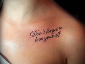 Фото тату надписи 'Don't forget to love yourself' на ключице девушки. Черный контур, минималистичный стиль, вдохновляющий девиз.