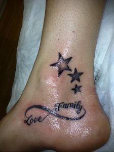 Фото татуировки на лодыжке с надписью 'Love Family', вписанной в символ бесконечности, и тремя звездами.
