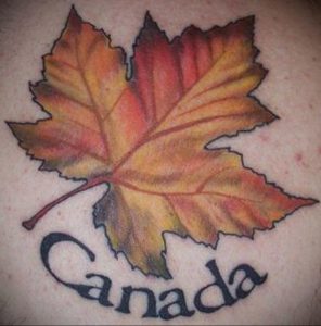 Фото татуировки: кленовый лист в осенних тонах с надписью "Canada", выполненной под ним, символизирует любовь к стране.