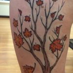 Фото татуировки кленового дерева на бедре. Черно-коричневый рисунок с детально прорисованными листьями.