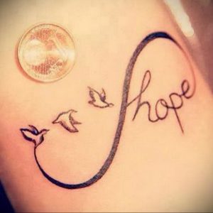 Фото тату на плече: символ бесконечности с летящими птицами и надписью 'hope'. Черно-белый рисунок татуировки в изящном стиле.