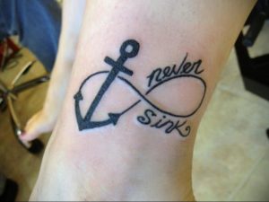 Фото тату бесконечности с изображением якоря и надписью 'never sink' на предплечье. Черно-белая татуировка, морская тематика.