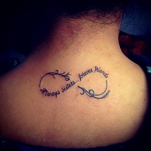 Фото тату бесконечность с надписью 'Always sisters... forever friends' на спине. Черно-белый рисунок татуировки в минималистичном стиле.
