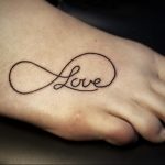 Фото минималистичной татуировки бесконечности с надписью 'Love' на стопе. Черно-белый контурный рисунок татуировки.