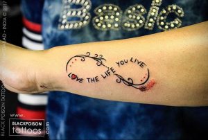 Фото тату бесконечности на руке с надписью 'love the life you live'. Черно-красный рисунок татуировки, символизирующий любовь к жизни.