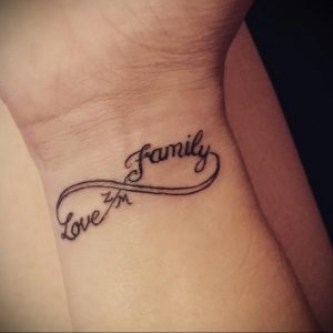 Фото тату бесконечности на запястье с надписями 'family' и 'love'. Черный рисунок татуировки, символизирующий любовь к семье.