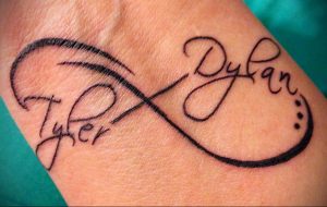 Фото тату на запястье: символ бесконечности с надписями "Tyler" и "Dylan". Элегантный и персонализированный рисунок татуировки.