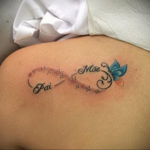 Фото тату на лопатке: символ бесконечности с надписями "Pai" и "Mãe" и изображением голубой бабочки. Красивый и трогательный рисунок татуировки.