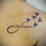 Фото тату бесконечность с летящими птицами и именем 'Rodrigo' на плече.