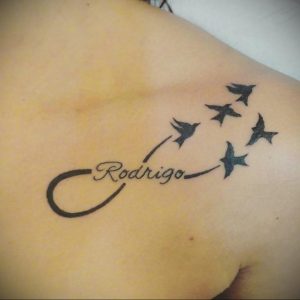 Фото тату бесконечность с летящими птицами и именем 'Rodrigo' на плече.