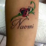 Фото тату божьей коровки с именем Naomi. Красивый рисунок татуировки на руке, сочетающий изображение насекомого и надпись.
