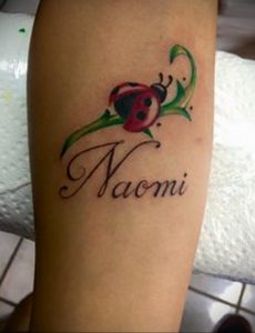 Фото тату божьей коровки с именем Naomi. Красивый рисунок татуировки на руке, сочетающий изображение насекомого и надпись.