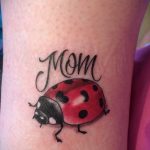 Фото тату божьей коровки с надписью "Mom" на руке. Нежный и трогательный рисунок, посвященный матери.