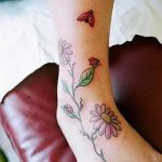 Фото тату божьей коровки, летящей среди ромашек на лодыжке. Нежный и романтичный рисунок.