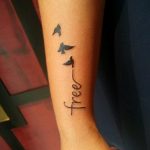 Фото тату с изображением трех силуэтов птиц и надписи 'free' на руке. Минималистичный дизайн и вдохновляющий смысл.
