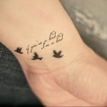 Фото тату: две маленькие птицы и надпись 'if you’re a bird I’m a bird' на запястье. Минимализм, каллиграфия, нежный дизайн.