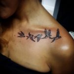 Фото татуировки на ключицах с изображением нескольких летящих птиц. Нежный и романтичный рисунок в черно-белых тонах.