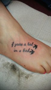 Фото тату на стопе: черная татуировка с надписью "if you're a bird im a bird" и двумя силуэтами птиц. Небольшой рисунок татуировки.