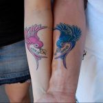 Фото парных тату ласточек на предплечьях. Розовая и голубая ласточки с датой, выполненные в традиционном стиле.