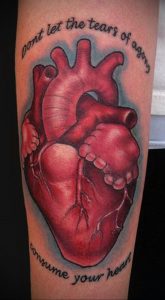 Фото тату: реалистичная татуировка сердца на руке с надписью 'Don't let the tears of agony consume your heart'.