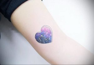 Фото тату: сердце, наполненное галактикой и звездами, акварельный стиль татуировки, яркий и красочный эскиз тату на руке.