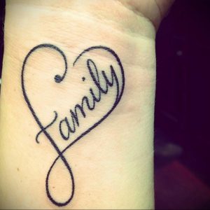 Фото тату с надписью 'Family' в форме сердца на запястье. Красивый и трогательный рисунок татуировки, символизирующий семейные ценности.