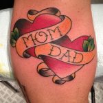 Фото тату: классическая татуировка сердца с надписью 'Mom Dad' на ленте, выполненная в традиционном стиле. Яркий и памятный рисунок татуировки.