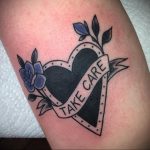 Фото тату сердца в стиле олдскул с надписью 'Take Care' на ленте. Классический рисунок татуировки с четкими контурами и яркими цветами.