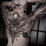 Фото тату крыльев ангела и позвоночника на спине. Детализированный черно-белый рисунок татуировки в стиле реализм с использованием дотворк техники.