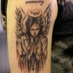 Фото тату ангела на плече с надписью 'In loving memory' и именем 'Sammy'. Черно-белый рисунок татуировки в стиле реализм.