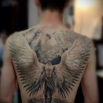 Фото тату ангела с огромными крыльями на спине. Детализированный рисунок в стиле реализм, создающий эффект присутствия.