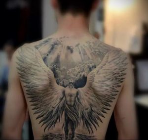Фото тату ангела с огромными крыльями на спине. Детализированный рисунок в стиле реализм, создающий эффект присутствия.